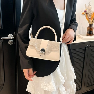 Beige crossbody handbag with glitter top and metal lock shown in a bright indoor setting