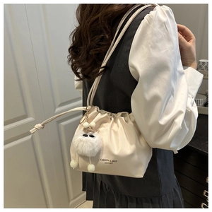 Detail view of off-white PU leather bucket bag with drawstring and plush pendant decoration