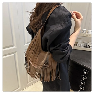 Detalle de bolso de hombro marrón oscuro con flecos de cuero y textura de borlas de moda