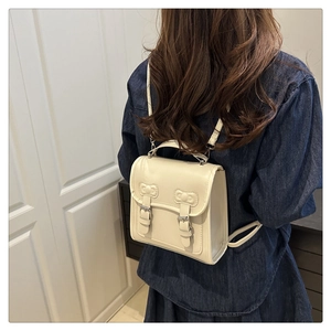 Mini sac à dos en similicuir crème avec surpiqûres nœud porté par le modèle