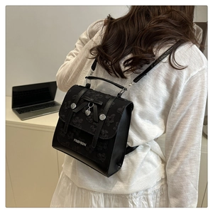 Close-up of black lace backpack featuring a ribbon bow and silver heart pendant