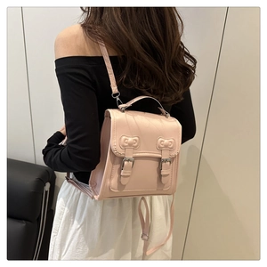 Close-up of pink PU leather backpack featuring decorative bows and metal buckle details