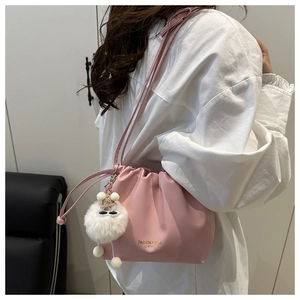 Detail of pink pleated bucket bag with gold lettering and cute white pompom charm