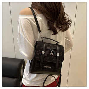 Close-up of black lace floral pattern and silver heart charm on a mini backpack
