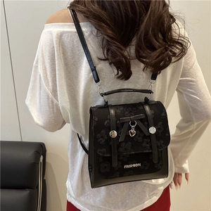 Fashionable black backpack with lace floral pattern, bow detail, and heart pendant