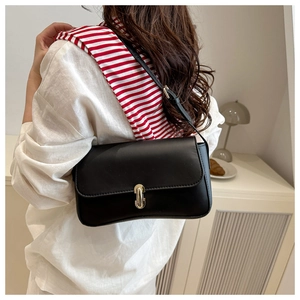 Close-up of black square bag with gold metal buckle worn with a white linen shirt