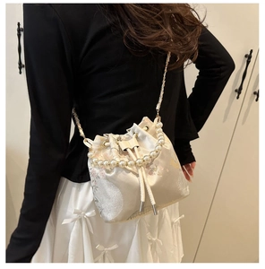 Detailed embroidery on cream bucket bag with elegant pearl handle and metal chain