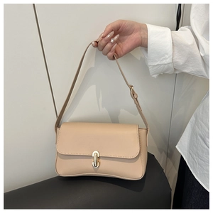 Detail of beige faux leather shoulder bag featuring a gold oval twist lock and adjustable strap