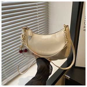 Vue détaillée du sac demi-lune en cuir verni crème avec breloque cerise et chaîne dorée