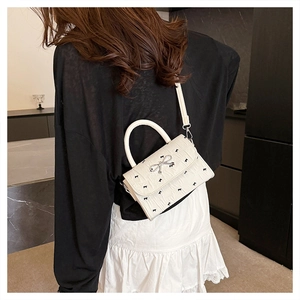 Detailed back view of a white bow print crossbody bag worn by a model in a lace skirt