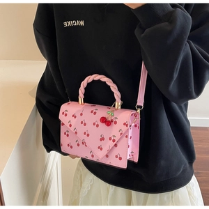 Détail du sac rose à imprimé cerise avec poignée tressée et breloques cerise 3D