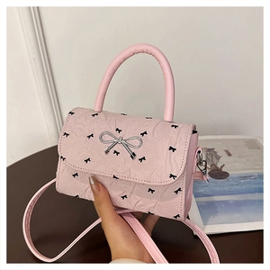 Detail of pink shoulder bag with black bow prints and silver metallic bow buckle closure