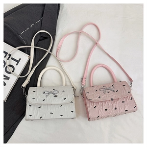 Detail view of stylish bow pattern square bags with silver metallic ribbon clasp and handles