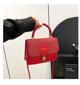 Detail of red glitter crossbody bag with gold lock and fashion circular patch on flap