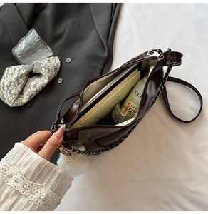 Detailed interior of glossy dark brown tote bag with metal chain and pom-pom charm
