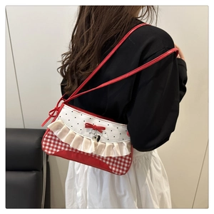 Detail of red gingham shoulder bag featuring ruffles, a bow, and a silver heart charm