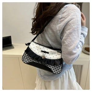 Close-up of lace-trimmed underarm bag with heart print and silver pendant detail