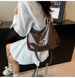 Detail view of large dark brown leather hobo bag with metal chain strap on model