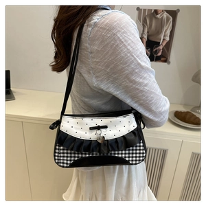Close-up of gingham pattern underarm bag with lace edges and a silver heart charm