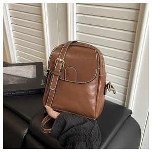 Détail du sac bandoulière marron caramel avec surpiqûres blanches et boucle métallique