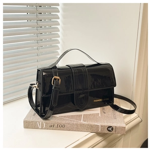 Close-up of black patent leather crossbody bag with gold text on hardcover books