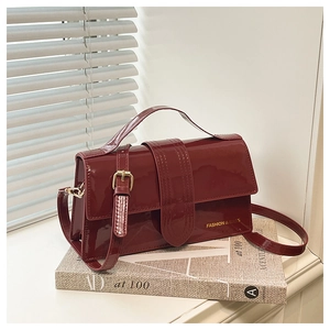 Detail of burgundy patent leather handbag with gold hardware and stylish top handle