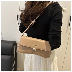 Detail of beige shoulder bag showing the golden oval metal buckle and curved bottom edge