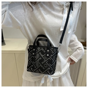 Detail of ethnic bucket bag featuring silver geometric embroidery and black leather strap