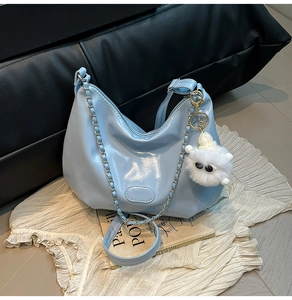 Detail of light blue glossy shoulder bag with silver chain and white plush charm accessory