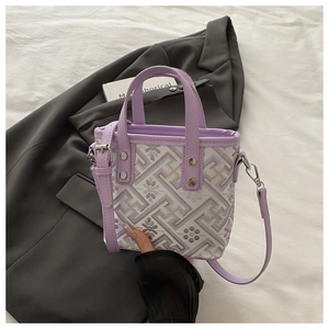 Detail of purple bucket bag featuring floral jacquard fabric and metal rivet hardware