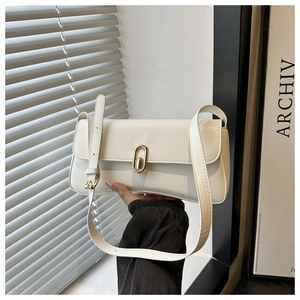 Close-up of cream leather underarm bag featuring a golden oval twist lock and flap