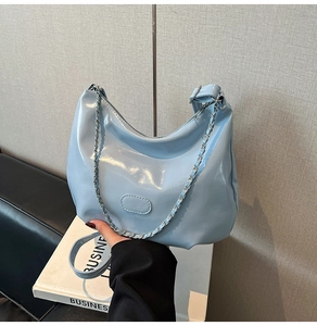 Macro view of light blue glossy patent leather surface and silver metal chain detail