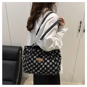 Close-up of black and white checkerboard tote bag with premium leather logo detail