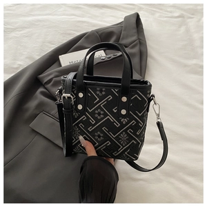 Detail of embroidered geometric patterns and floral textures on a black tote bag