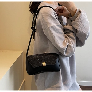 Detail of elegant black sequin shoulder bag featuring a gold buckle and knotted strap design