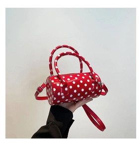 Detail view of red polka dot barrel bag with silver zippers and adjustable strap