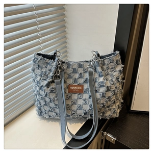 Close-up of checkered denim tote bag with frayed texture and brown leather label