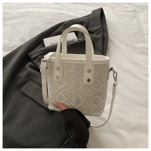 Detail view of jacquard floral handbag with silver hardware on a black blazer background