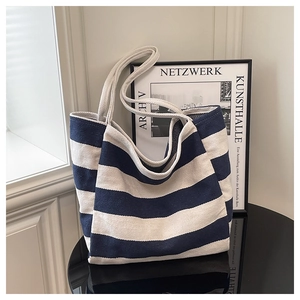 Detail of blue and white striped canvas tote bag with thick rope handles on a black surface