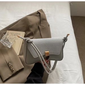 Detail of grey shoulder bag featuring woven texture flap and golden square lock