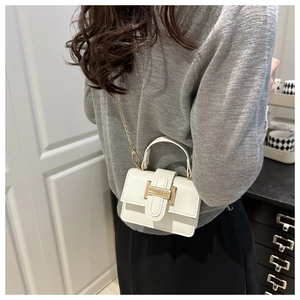 Close-up of white mini square handbag with gold buckle and chain strap shown on model