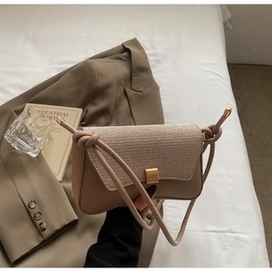 Detail of beige leather baguette bag with sequined flap and knotted shoulder strap
