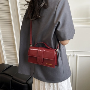 Glossy dark red patent leather crossbody bag with top handle and gold hardware detail