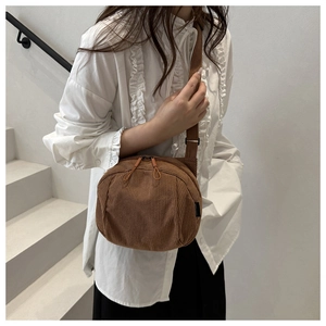 Brown corduroy crossbody bag with zipper and adjustable strap on a lifestyle model