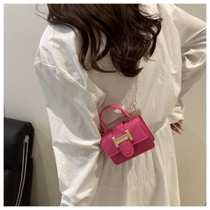 Dettaglio della mini borsa fucsia con chiusura a H dorata e tracolla a catena in metallo