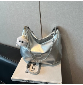 Detail of silver metallic hobo bag with chain strap and cute white lamb pendant charm