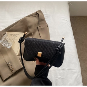 Detail of black textured flap bag with glitter fabric and gold rectangular buckle