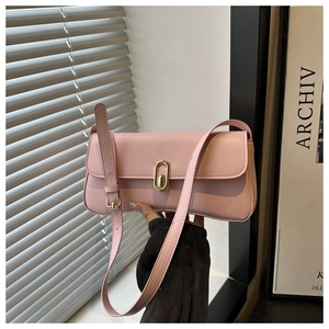Close-up of pink leather baguette bag with a stylish gold buckle and long strap