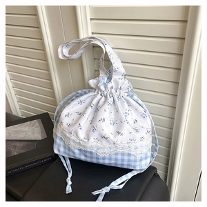 Detail of floral and plaid patchwork drawstring bag with delicate white lace trim