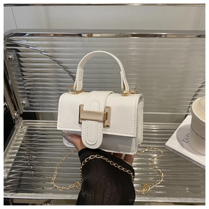 Close-up of white crossbody bag with gold rectangular metal buckle and chain strap